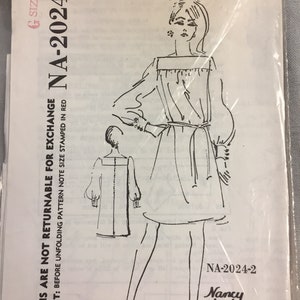 May include: A black and white line drawing of a woman wearing a dress with a boat neck and long sleeves. The dress has a belt at the waist. The drawing is on a white background with the text "Spadea Designer Pattern" and "NA-2024-2" in black.