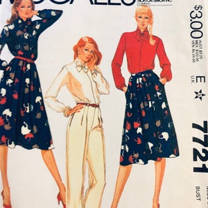 May include: A sewing pattern for a blouse and skirt. The pattern is from McCall's and is for size E 7721. The pattern shows three different styles of the blouse and skirt. The blouse is a long-sleeved, button-up shirt with a bow tie. The skirt is a knee-length skirt with a print of white cats on a dark blue background.
