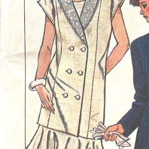 Puede incluir: Ilustración de un vestido vintage color crema con cuello decorativo y falda plisada. El vestido tiene un diseño cruzado con cuatro botones. La modelo lleva una pulsera blanca.