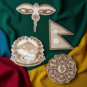 Może przedstawiać: Cztery drewniane wycięcia o skomplikowanych wzorach są wyświetlane na kolorowym tle. Wycięcia obejmują symbol oka, flagę, emblemat kwiatowy z tekstem i okrągły wzór z pismem. Drewno ma naturalny, jasnobrązowy kolor.