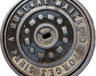 Op de afbeelding: Een zwart metalen putdeksel met de tekst "VILLE DE PARIS FORGES DE MAITRES DURENNE" rond de rand.