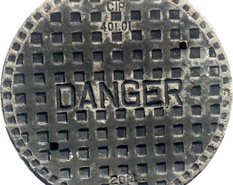 May include: A circular, dark gray manhole cover with a grid pattern and the word "DANGER" in large, bold letters. The cover also features the numbers "40101" and "2014".