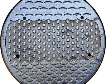 May include: A circular, weathered metal storm sewer cover. The design features water droplet and wave patterns. The text "STORM SEWER" is at the top, and "CITY OF VANCOUVER" is at the bottom.