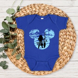 May include: A royal blue baby onesie with a blue and white Mickey Mouse head design. The Mickey Mouse head has a silhouette of Moana inside with the text "Moana" underneath.