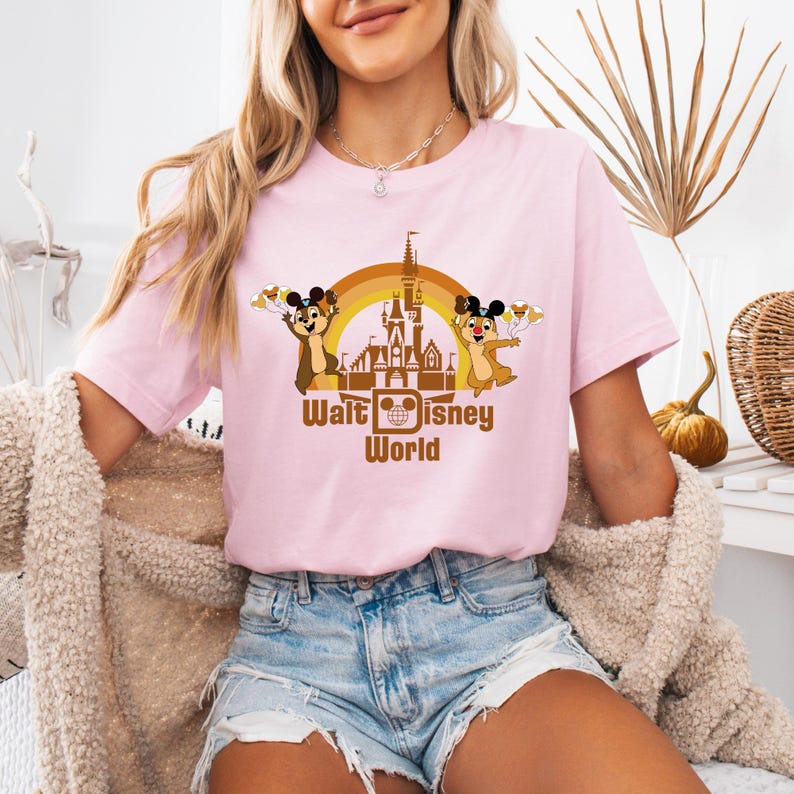May include: A pink t-shirt with a graphic of Chip and Dale in front of the Walt Disney World castle. The graphic is in brown, orange, and yellow. The text "Walt Disney World" is below the graphic.