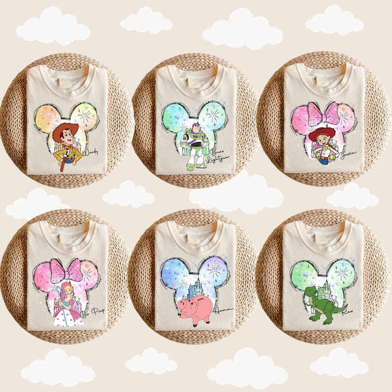 Puede incluir: Seis camisetas blancas con diferentes personajes de Disney en una silueta de oreja de Mickey. Los personajes son Woody, Buzz Lightyear, Jessie, Bella, Hamm y Rex. Cada camiseta tiene el nombre del personaje escrito debajo de la silueta.
