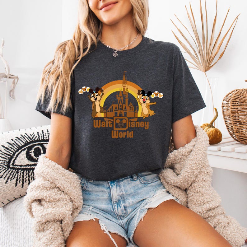 May include: A dark grey t-shirt with a graphic of Chip and Dale in front of the Cinderella Castle at Walt Disney World. The graphic includes a rainbow arch and the text "Walt Disney World".