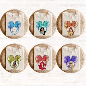 Pu&ograve; includere: Sei magliette bianche con diversi personaggi di principesse Disney in un design a orecchie di Topolino. Ogni maglietta presenta una principessa diversa: Ariel, Belle, Jasmine, Cenerentola, Biancaneve ed Elsa.