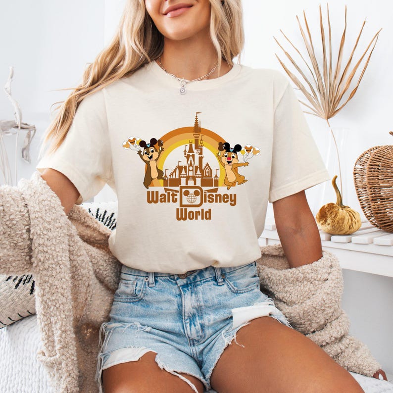 May include: A white t-shirt with a brown cartoon image of Chip and Dale in front of the Cinderella's Castle at Walt Disney World. The text 'Walt Disney World' is printed below the image.