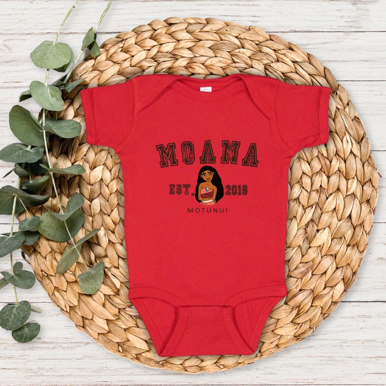 May include: Red baby onesie with a black graphic of Moana from the Disney movie Moana. The graphic includes the text "Moana Est. 2016 Motunui".