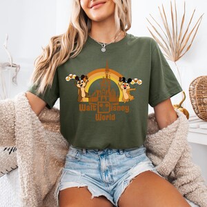 May include: A green t-shirt with a retro-style graphic of Chip and Dale in front of the Cinderella Castle at Walt Disney World. The graphic includes a rainbow and the text "Walt Disney World".