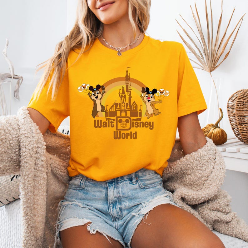May include: A yellow t-shirt with a graphic of Chip and Dale in front of the Cinderella Castle at Walt Disney World. The text "Walt Disney World" is printed below the graphic.