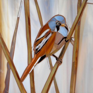 Könnte beinhalten: Ein Mosaik-Kunstwerk, das einen braunen und blauen Vogel zeigt, der auf einem Ast sitzt, vor einem weißen Hintergrund.