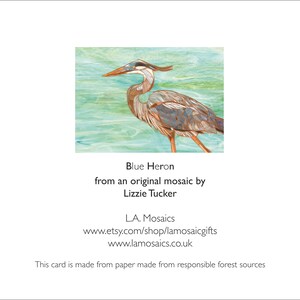 May include: A mosaic artwork of a blue heron standing in water. The artwork is made of small pieces of glass and tile. The heron is a vibrant blue with brown and gray accents. The water is a light blue and green.