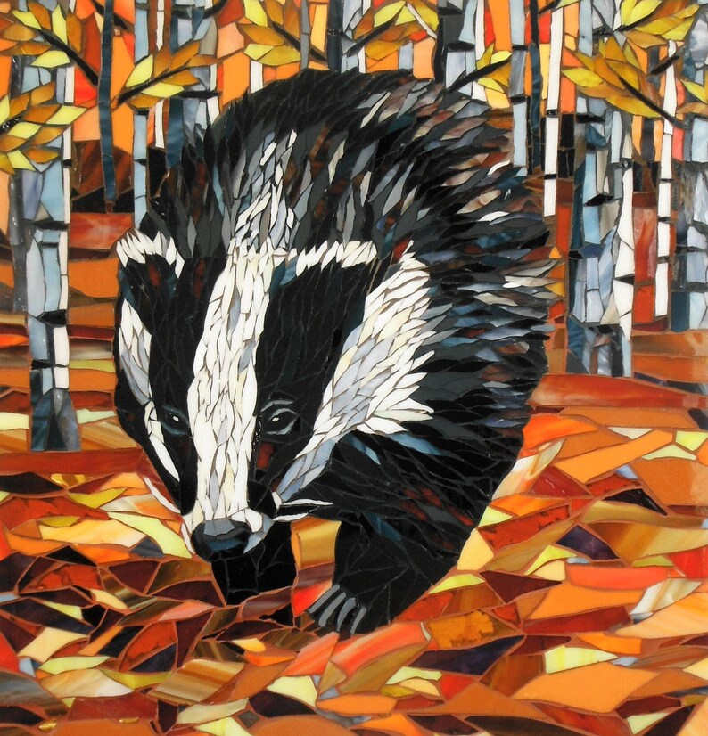 May include: A mosaic artwork depicting a badger walking through a forest of birch trees. The badger is black and white with a white stripe down its face. The trees are white with brown bark and yellow leaves. The ground is covered in orange, brown, and yellow leaves.