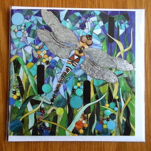K&ouml;nnte beinhalten: Eine Mosaik-Kunstkarte mit einer Libelle mit silbernen Fl&uuml;geln und einem bunten K&ouml;rper, umgeben von gr&uuml;nen Schilf und blauen und gr&uuml;nen Mosaikfliesen.
