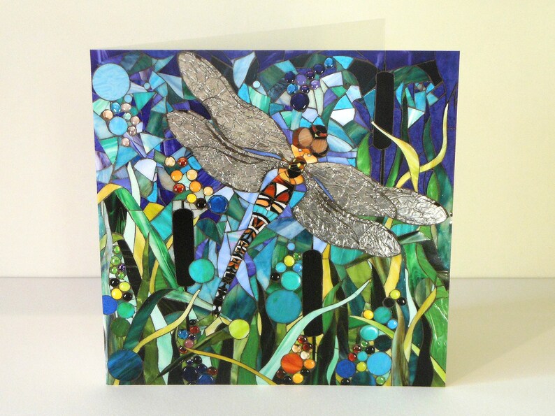 K&ouml;nnte beinhalten: Ein Mosaik-Kunstwerk, das eine Libelle mit silbernen Fl&uuml;geln vor einem Hintergrund aus blauen, gr&uuml;nen und gelben Glasfliesen zeigt.