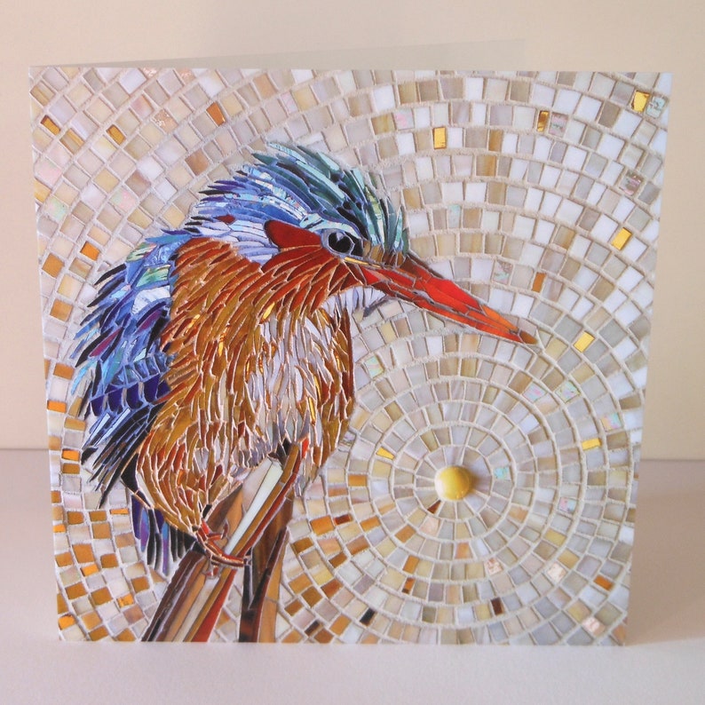 May include: A mosaic art piece of a kingfisher bird with blue, green, red, and brown feathers. The bird is perched on a branch against a background of white, gold, and beige mosaic tiles.