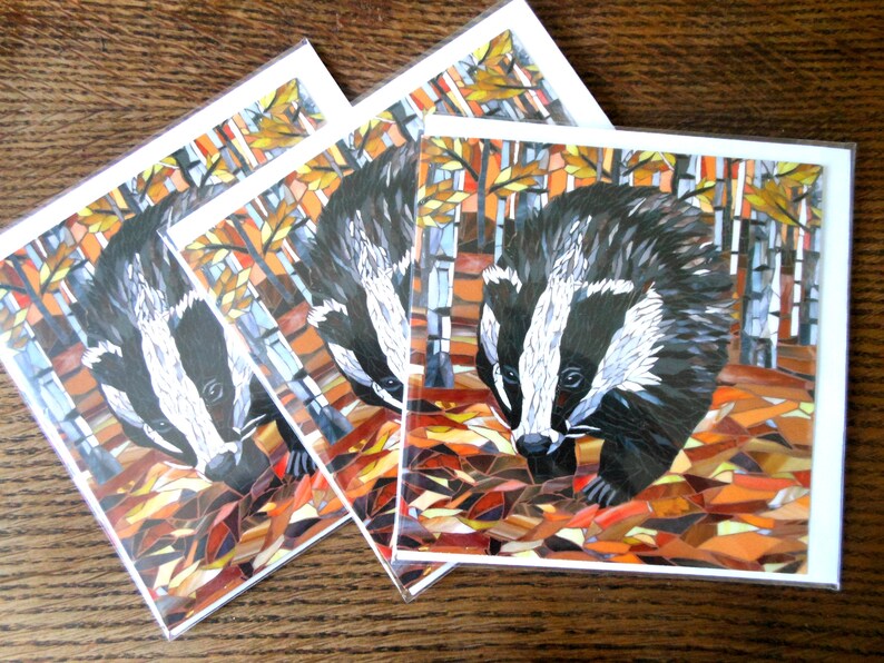 May include: Three cards with a mosaic illustration of a badger in an autumn forest. The badger is black and white with a white stripe down its face. The forest is made up of brown, orange, and yellow leaves.