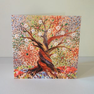 May include: A mosaic art card featuring a colourful tree with white flowers and a brown trunk. The background is a mix of red, orange, green, and blue mosaic tiles.