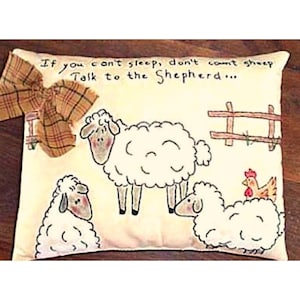 May include: Cream-colored pillow with a hand-drawn design of sheep, a fence, and a chicken. The pillow has a plaid bow on the left side and the text "If you can't sleep, don't count sheep, Talk to the Shepherd..."