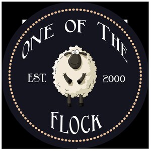 May include: A black and white circle with a white sheep in the center. The sheep has a black face and black legs. The text "One of the Flock" is written in a white arc above the sheep. The text "Est. 2000" is written in white below the sheep.