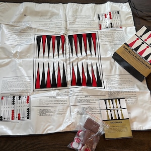 May include: A white fabric game board with black and red triangles, instructions, and a separate booklet titled "Backgammon Easy - Gain Advantage on the Board".
