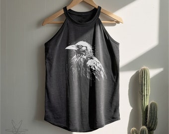 May include: A dark gray sleeveless tank top featuring a white graphic illustration of a raven in profile. The garment has a high neckline with wide arm openings and a curved hemline, hanging on a wooden hanger against a plain wall.