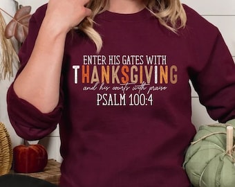 May include: A maroon sweatshirt with the text "Enter his gates with thanksgiving and his courts with praise Psalm 100:4" in orange and white lettering. The model is wearing black leggings with holes in the knees.