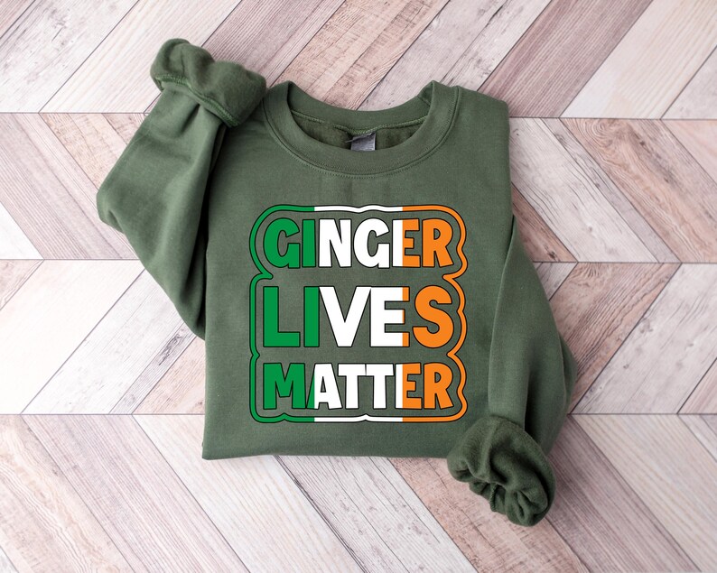 May include: Green sweatshirt with the text "Ginger Lives Matter" in white and orange letters inside a green, white, and orange rectangle.