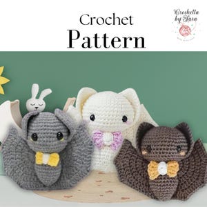 May include: Crochet pattern for three amigurumi bats. One bat is gray with yellow bow tie, one is brown with yellow bow tie, and one is white with pink bow tie. The bats are sitting on a light brown surface.