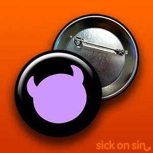 K&ouml;nnte beinhalten: Ein schwarzer Button mit einem lila Teufelsgesicht-Design. Der Button ist rund und gl&auml;nzend. Der Text "sick on sin" befindet sich unten rechts. Der Button befindet sich auf einem orangefarbenen Hintergrund.
