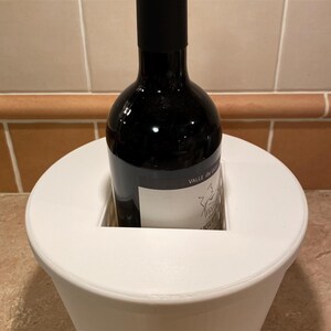 May include: White ceramic wine bottle cooler with a bottle of red wine inside. The bottle label reads "Valle de Uco, Mendoza, Argentina".