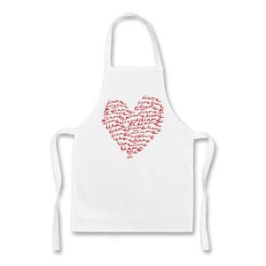 以下が含まれることがあります： 赤いハート型のデザインが施された白いエプロン。ハートは、筆記体で繰り返される「Ti Amo」という言葉で構成されています。エプロンには首のループとウエストのネクタイが付いています。