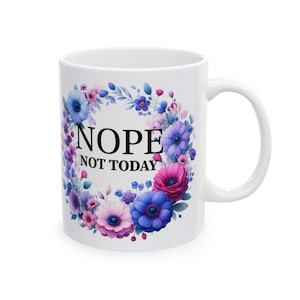 May include: White ceramic mug with a floral wreath design in shades of pink, purple, and blue. The text "NOPE NOT TODAY" is printed in black inside the wreath.