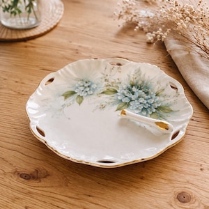 Hand-painted floral porcelain cut-out plate with gold trim and finger loop hole. 7 in