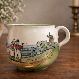 Hand-painted German ceramic creamer with Dutch children and windmill scene.