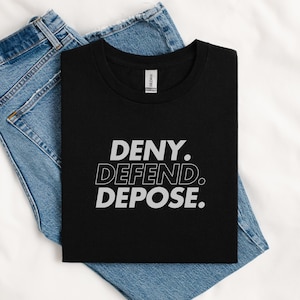 Può includere: Maglietta nera con testo bianco che dice "DENY. DEFEND. DEPOSE."