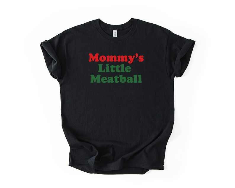 May include: Black t-shirt featuring the text "Mommy's Little Meatball" in red and green. The shirt has a crew neck and is made of a soft fabric. A casual, comfortable item of clothing.