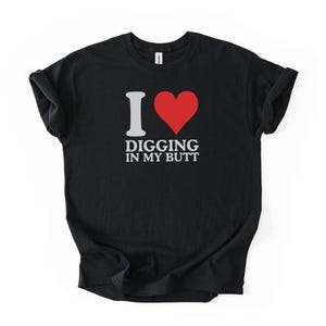 Puede incluir: Camiseta negra con el texto "I ❤️ Digging in my Butt" en blanco y un corazón rojo. La camiseta está hecha de un material suave y tiene mangas cortas.