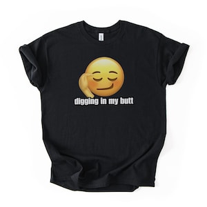 May include: Black t-shirt featuring a yellow emoji with a hand on its face and the text "digging in my butt" in white. The shirt is made of a soft material and has short sleeves.
