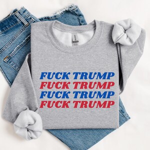 May include: A gray sweatshirt with the phrase "FUCK TRUMP" repeated four times in red and blue lettering.