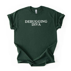 Könnte beinhalten: Dunkelgrünes T-Shirt mit dem weißen Aufdruck „DEBUGGING DIVA“ auf der Brust. Das Shirt hat kurze Ärmel und einen Rundhalsausschnitt. Der Stoff scheint ein weiches, meliertes Material zu sein.