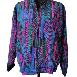 May include: A black zip-up jacket with a vibrant, patterned design. The jacket features a mix of pink, blue, and green geometric shapes and abstract patterns. The jacket is displayed on a black mannequin.