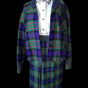 Könnte beinhalten: Ein Vintage-Rockanzug mit passendem Blazer und weißem Hemd mit Kragen. Der Anzug hat ein grün-violett-schwarz-rotes Karomuster. Der Blazer hat schwarze Knöpfe und einen Kragen. Der Rock ist plissiert.