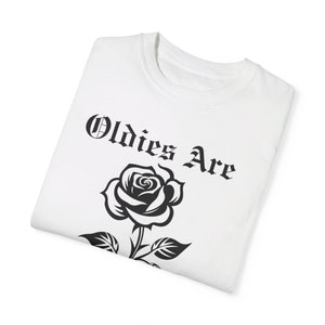 May include: White t-shirt featuring a black rose and the text "Oldies Are" in a gothic font.