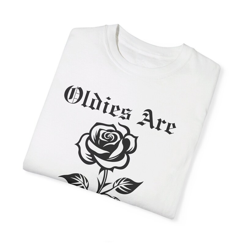 May include: White t-shirt featuring a black rose and the text "Oldies Are" in a gothic font.