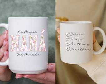 May include: Two white ceramic mugs. One mug features a floral design and the text "La Mejor MAMÁ Del Mundo". The other mug has the text "Jessica, Maya, Anthony, Jonathan" with a heart symbol before each name.