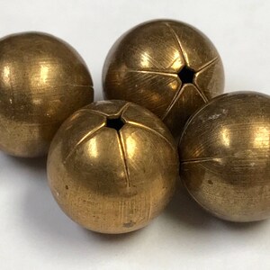 May include: Four antique brass spherical beads. Each bead has a star-shaped design cut into the surface. The beads have a warm, golden color and a slightly aged appearance. These beads could be used for jewelry making or other craft projects.