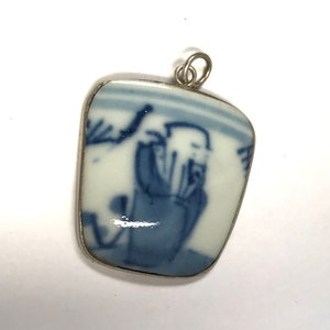 Peut inclure: Un pendentif en argent avec un médaillon en porcelaine bleue et blanche représentant un personnage chinois dans un paysage.